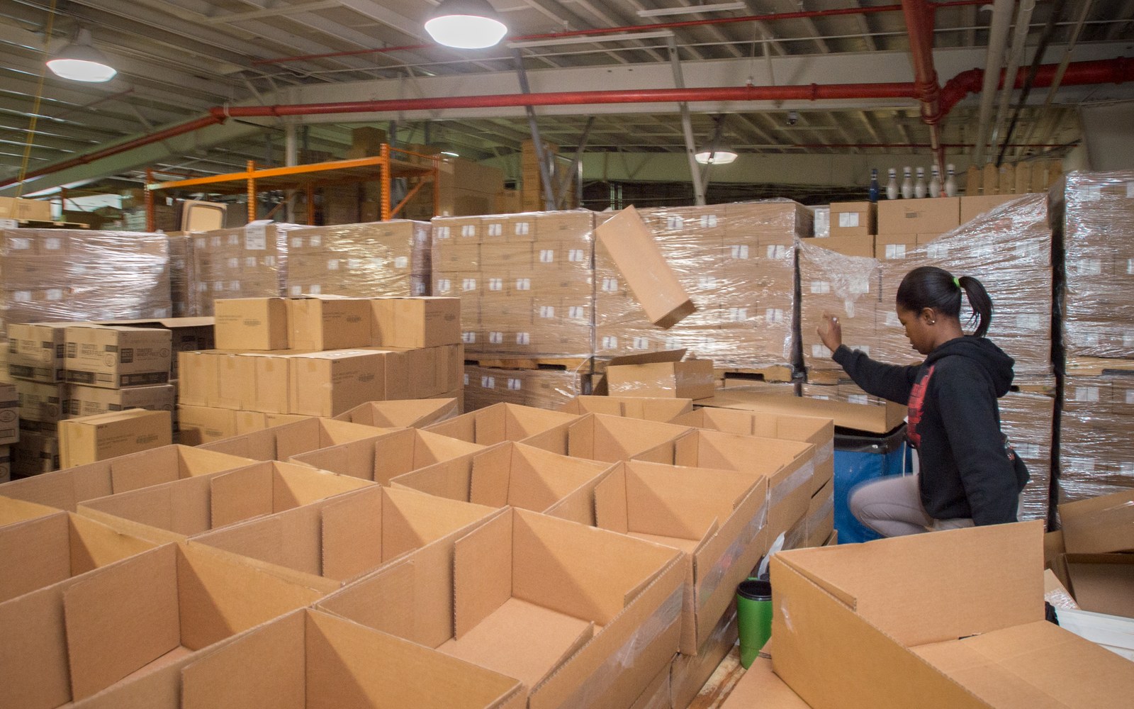 A worker counting stock in a warehouse aisle